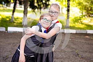 A schoolgirl in a white blouse with a red tie, with a bow and her little brother with blue tie and glasse in the class. Back to