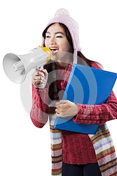 Schoolgirl in winter wear shouting with megaphone