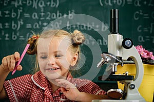 Schoolgirl work with laboratory equipment on chemistry or biology class. Little girl with microscope in school