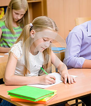 Schoolgirl writes the exam in class photo
