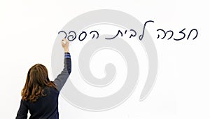 Schoolgirl writing Back to school in Hebrew on a whiteboard