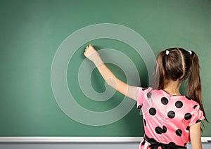 Schoolgirl writing on empty blackboard, back view