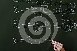 schoolgirl writing high school maths formula with chalk on blackboard