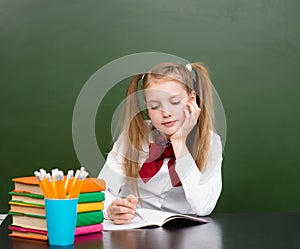 Schoolgirl wrote in a notebook in the classroom