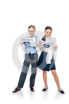 Schoolgirls in formal wear reading business newspapers On White.