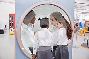 Schoolgirls looking in a magnifying mirror at science centre