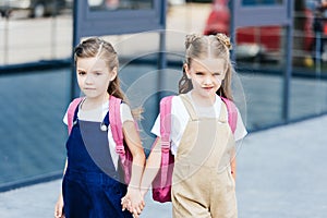 schoolgirls with pink backpacks holding hands