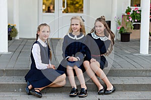 Schoolgirls in school uniform rest on a break near the school