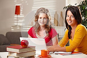 Schoolgirls smiling at table.