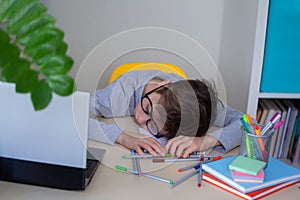 Schoolkid is bored with studying at home. Child fell asleep doing homework at the table