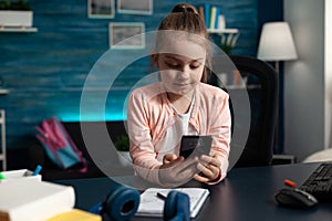 Schoolkid holding modern smartphone reading literature story