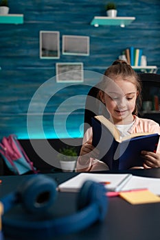 Schoolkid reader smiling while reading edcuational book studying for school literature exam
