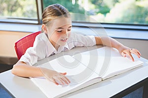 Schoolkid reading braille book in classroom photo