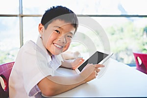 Schoolkid using digital tablet in classroom photo