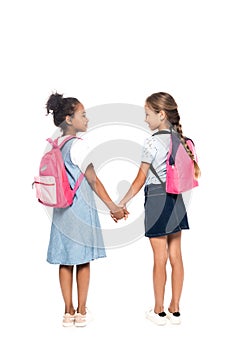 Schoolkids with backpacks holding hands and