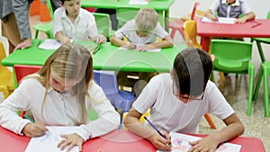 schoolkids drawing with cheerful female teacher at classroom