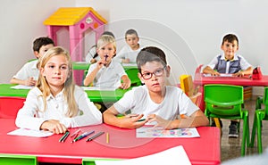 Schoolkids sitting in classroom attentively listening teacher