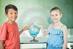 Schoolkids studying globe in classroom