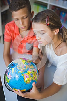 Schoolkids studying globe in library