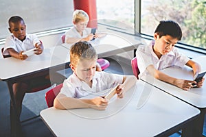 Schoolkids using mobile phone in classroom