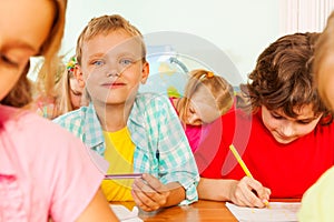 Schoolmates sit together in classroom and write