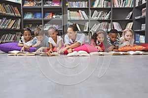 Schoolteacher reading books with his school kids in library