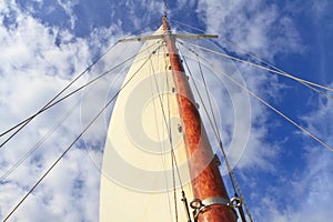 Schooner mast and sail in blue sky