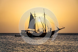 A schooner ship silhouetted against the sunset