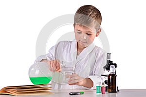 Science boy pours green liquid from flask into glass