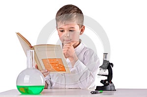 Science boy reads book at chemistry lab at the desk