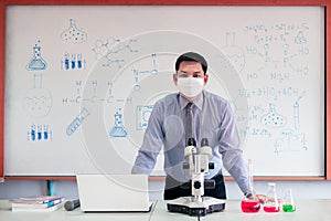 Science chemistry teacher teaching with microscope and laptop in the classroom