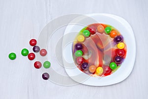 Science experiment for kids. Circle of colored candies on white plate