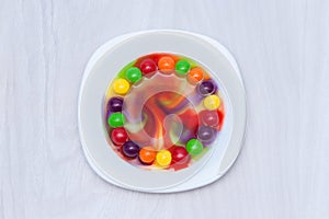 Science experiment for kids. Circle of colored candies on white plate