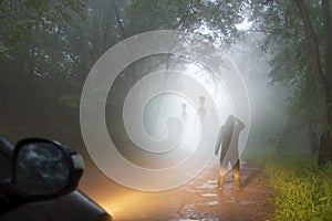 A science fiction concept of a man looking at aliens coming out the mist on a foggy, spooky forest road in the evening. Highlighte