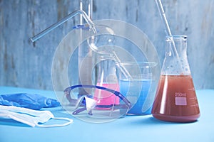 Science glassware with colored liquid, glasses, mask, gloves