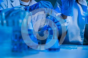 Science and medicine, scientist analyzing and dropping a sample into a glassware, experiments containing chemical liquid in