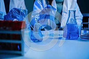 Science and medicine, scientist analyzing and dropping a sample into a glassware, experiments containing chemical liquid in