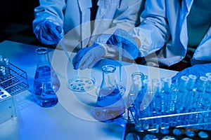 Science and medicine, scientist analyzing and dropping a sample into a glassware, experiments containing chemical liquid in