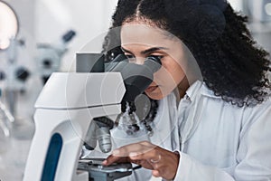 Science, microscope and sample with a doctor black woman at work in a lab for innovation or research. Medical, analysis