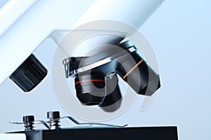 Science. Modern microscope on light blue background, closeup
