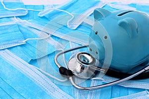 On medical masks lies a stethoscope and a piggy bank.