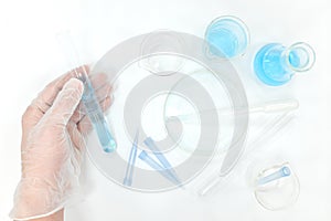 Science research laboratory flat lay. Scientist hands working on blue chemicals.