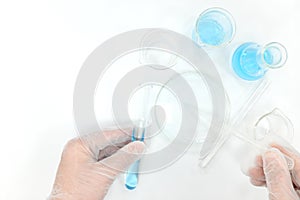Science research laboratory flat lay. Scientist hands working on blue chemicals.