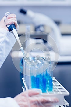 Science student using pipette in the lab to fill test tubes