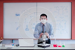 Science teacher wearingmask and   teaching with using microscope in the classroom