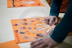 scientific activity for children, drawing and collage of the bones of the hand. On a decorated orange sheet a hand was drawn and