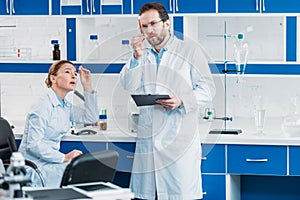 scientific researcher looking at flask with reagent in hand with colleague near