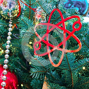 Scientific symbol of the atom as decoration at New Years celebration, golden bokeh. Winter christmas tree with bauble, copy space