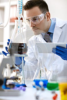 Scientist analysis chemical experiment with tablet