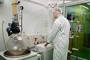 Scientist apothecary extract using cannabis extraction machine in laboratory.